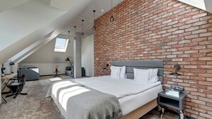 A bedroom with a brick wall, a bed, a desk, and a chair. - Grano Hotel**** Gdańsk Riverside (Gdansk)