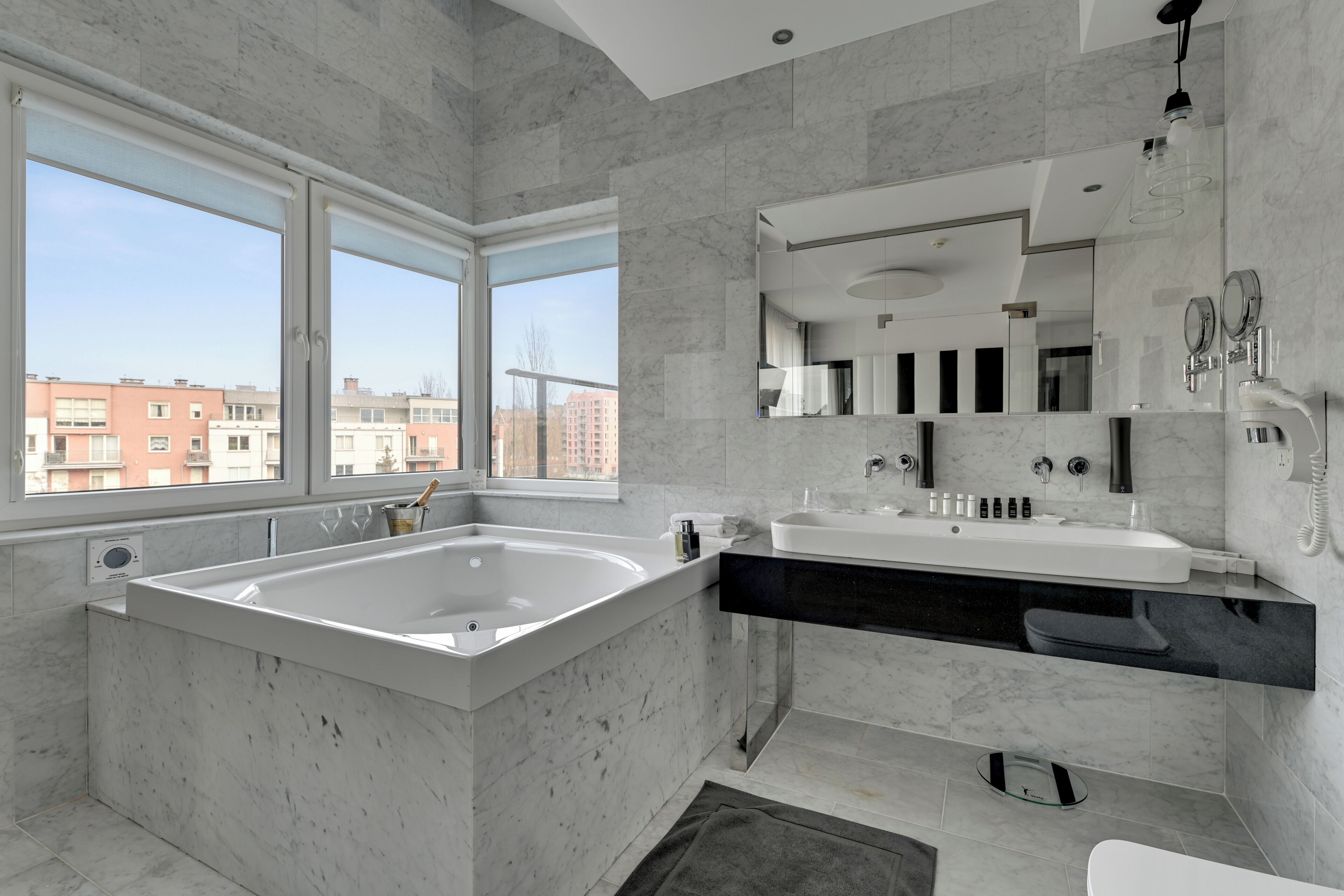 A modern bathroom with a large bathtub, a double sink vanity, and a large mirror.