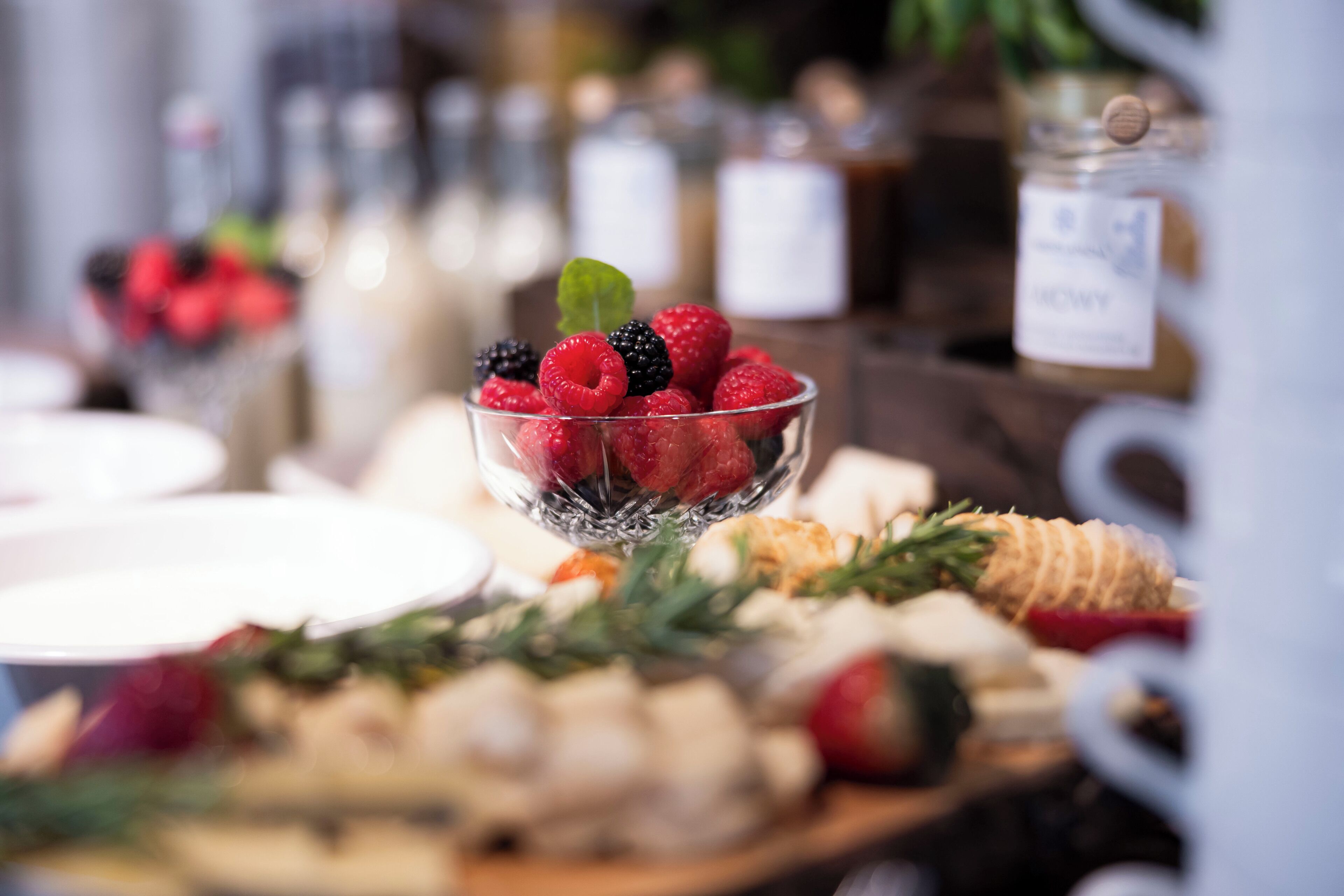 Un bufé con una variedad de alimentos, incluyendo frutas, quesos y pasteles.