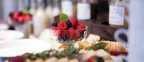 Un bufé con una variedad de alimentos, incluyendo frutas, quesos y pasteles.