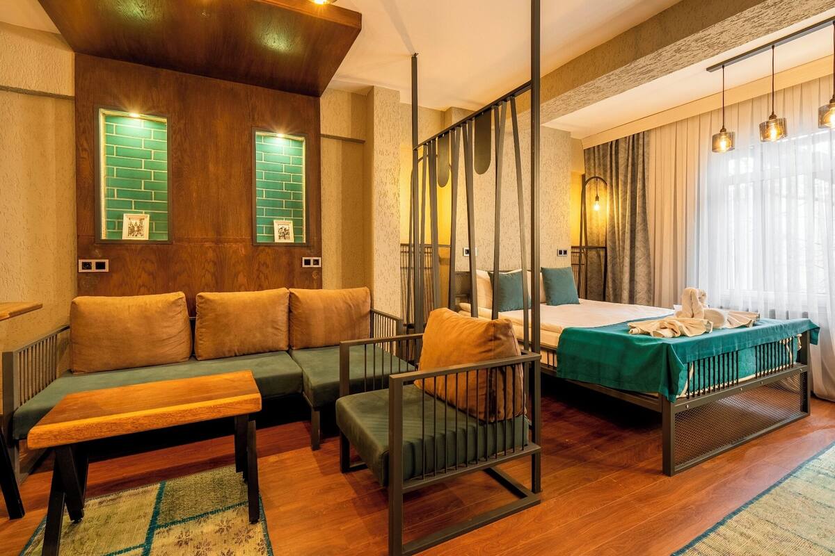 A room with a bed, a bench, a sofa, and a small table.