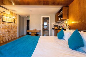 Une chambre à coucher avec un lit, une couverture bleue et des coussins turquoise.