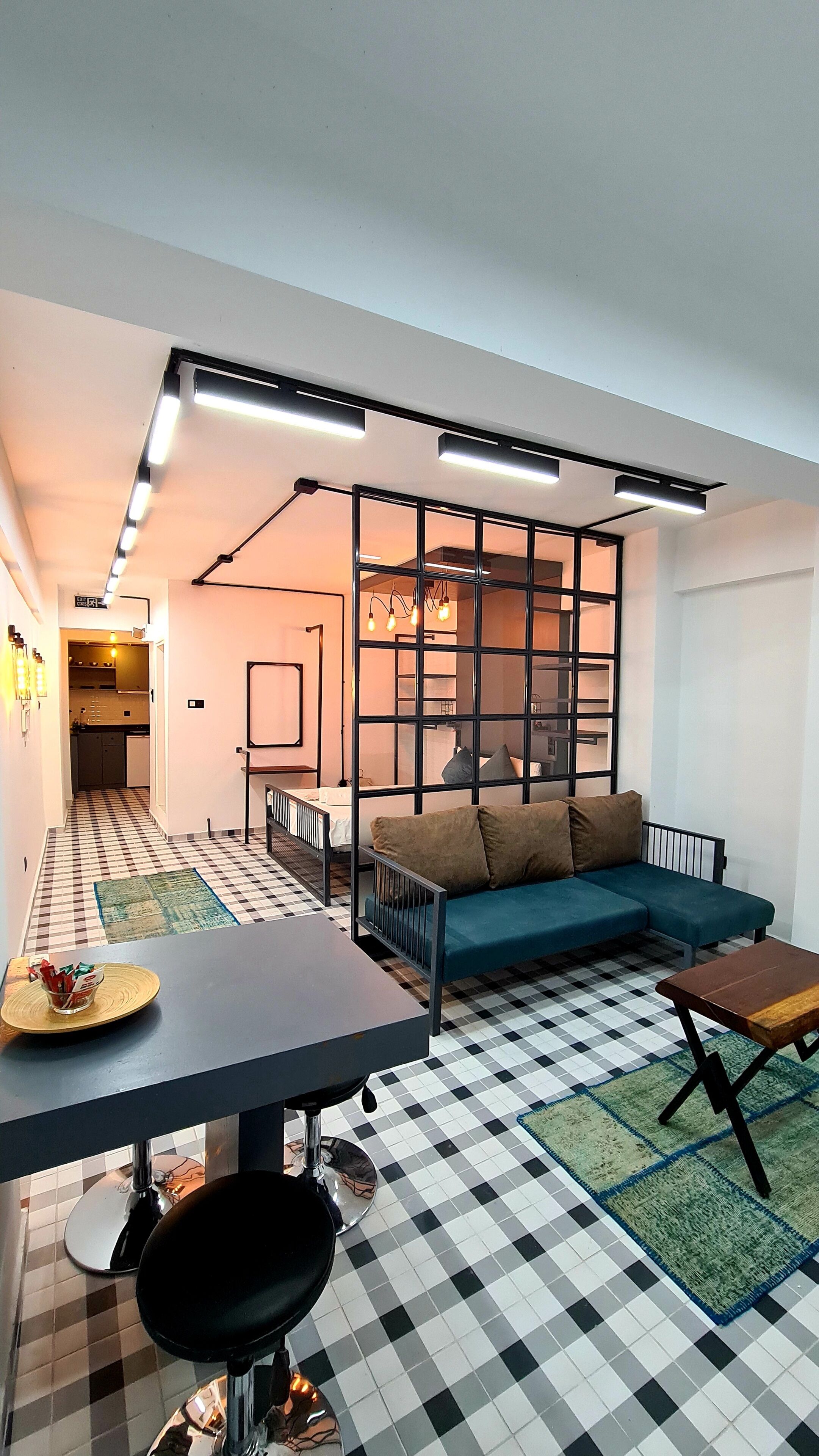 A compact living space with a kitchenette, a sofa, a dining table, and a patterned floor.