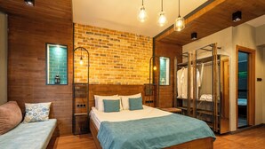 Un dormitorio con una cama de madera, un banco, una pared de ladrillo y un armario.