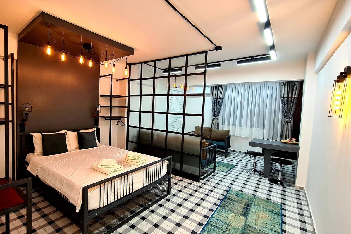A modern bedroom with a bed, a sofa, a desk, and a view of the outside.