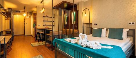 A hotel room with a bed, a desk, a chair, and a mirror.