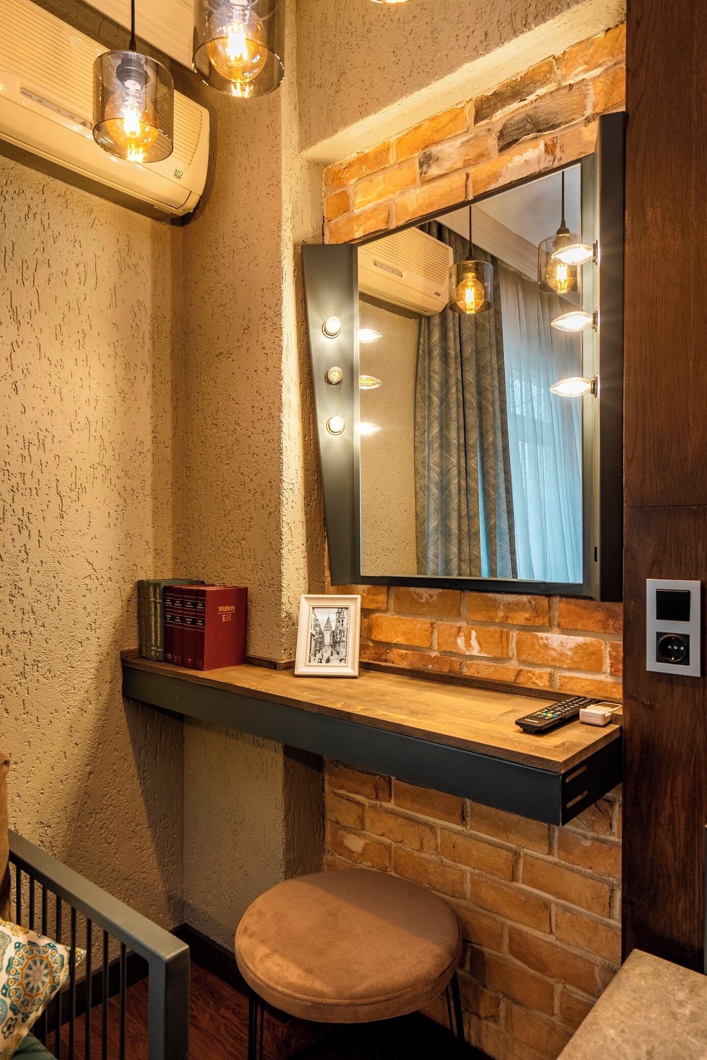 Un baño con pared de ladrillo, tocador con espejo y lámpara colgante.