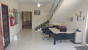 Hotellin toimisto, jossa on työpöytiä, tuoleja, sammutin, roskakori ja portaikko.