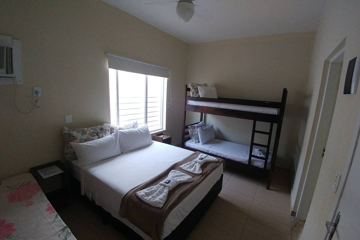 A bedroom with a bunk bed, a single bed, a window with blinds, and a ceiling fan.