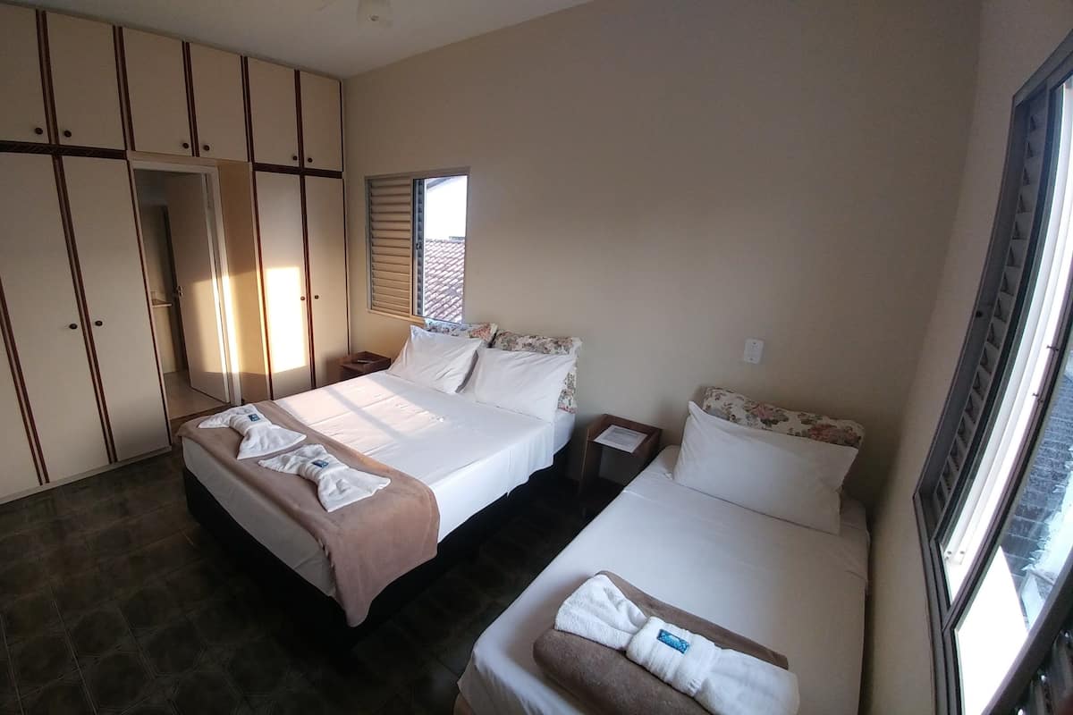 A bedroom with a large bed, a smaller bed, a wardrobe, and a window.