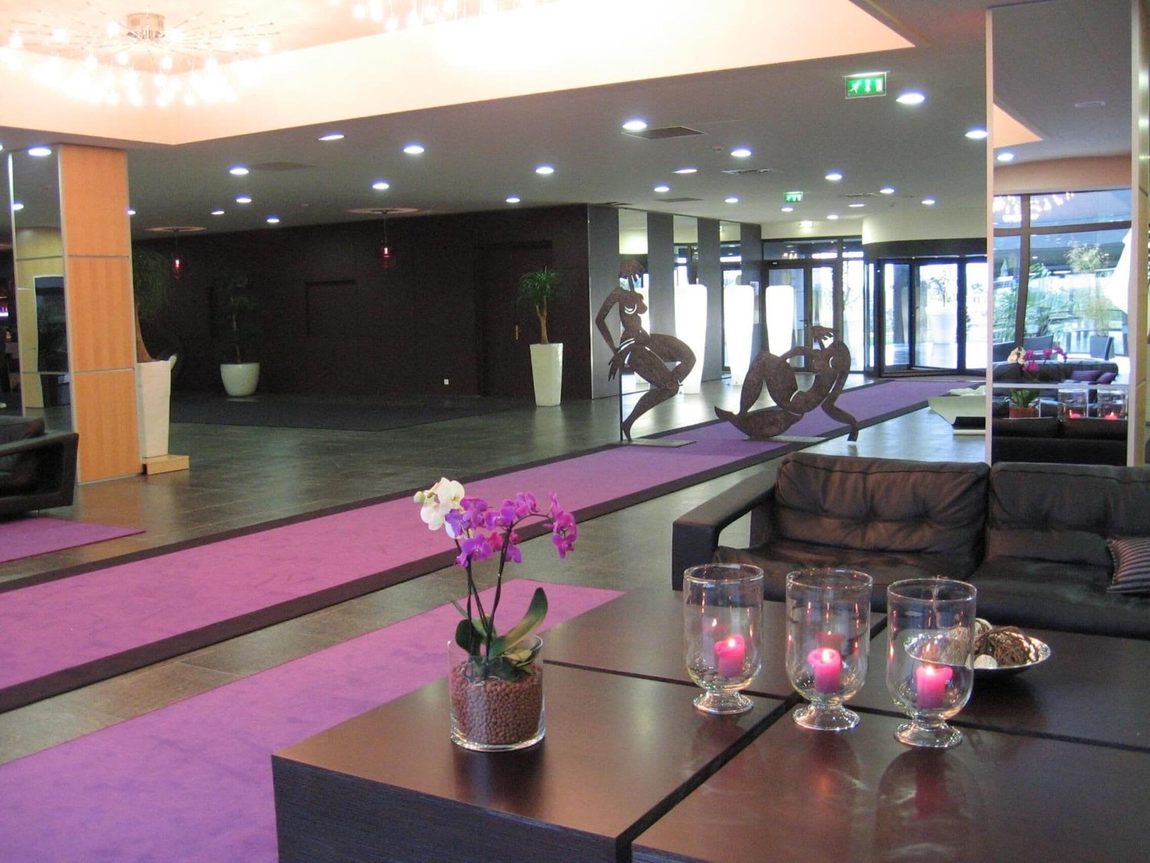 A modern lobby with a reception desk, seating area, and large windows.