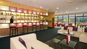 A bar area with a variety of bottles, a counter, and seating. - Residhome Suites Paris Sénart (Lieusaint)