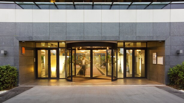A modern building entrance with a revolving door and glass doors. - Residhome Suites Paris Sénart (Lieusaint)
