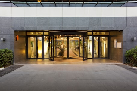 A modern building entrance with a revolving door and glass doors.