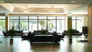 A spacious lobby with leather sofas, a central coffee table, and potted plants. Large windows provide natural light and views of the outdoors. - Residhome Suites Paris Sénart (Lieusaint)