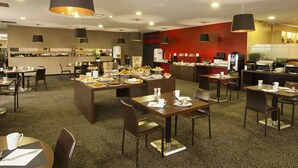 A modern dining area with multiple tables and chairs, a buffet setup, and a kitchen in the background. - Residhome Suites Paris Sénart (Lieusaint)