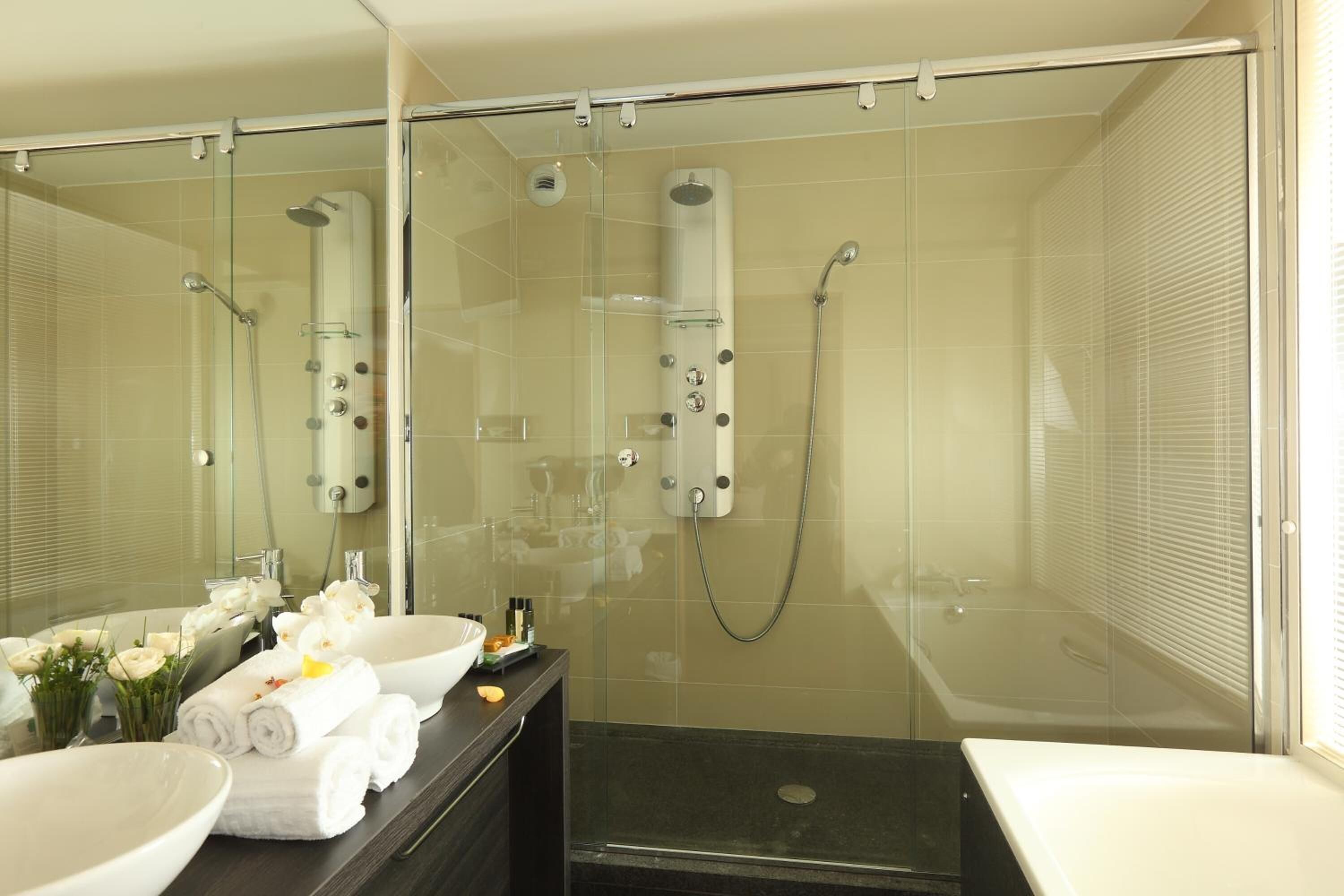 Un baño moderno con ducha envuelta en vidrio, una bañera y un tocador con un espejo grande.