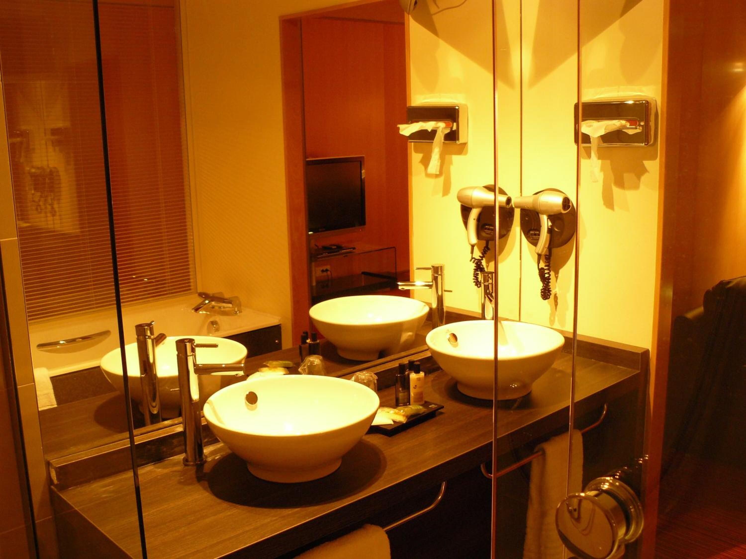Un baño con dos lavamanos, un espejo, un secador de pelo y un perchero para toallas.
