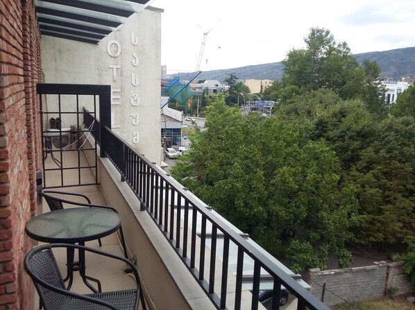 A balcony with a table and chairs, a view of a construction site, and a building with a sign.