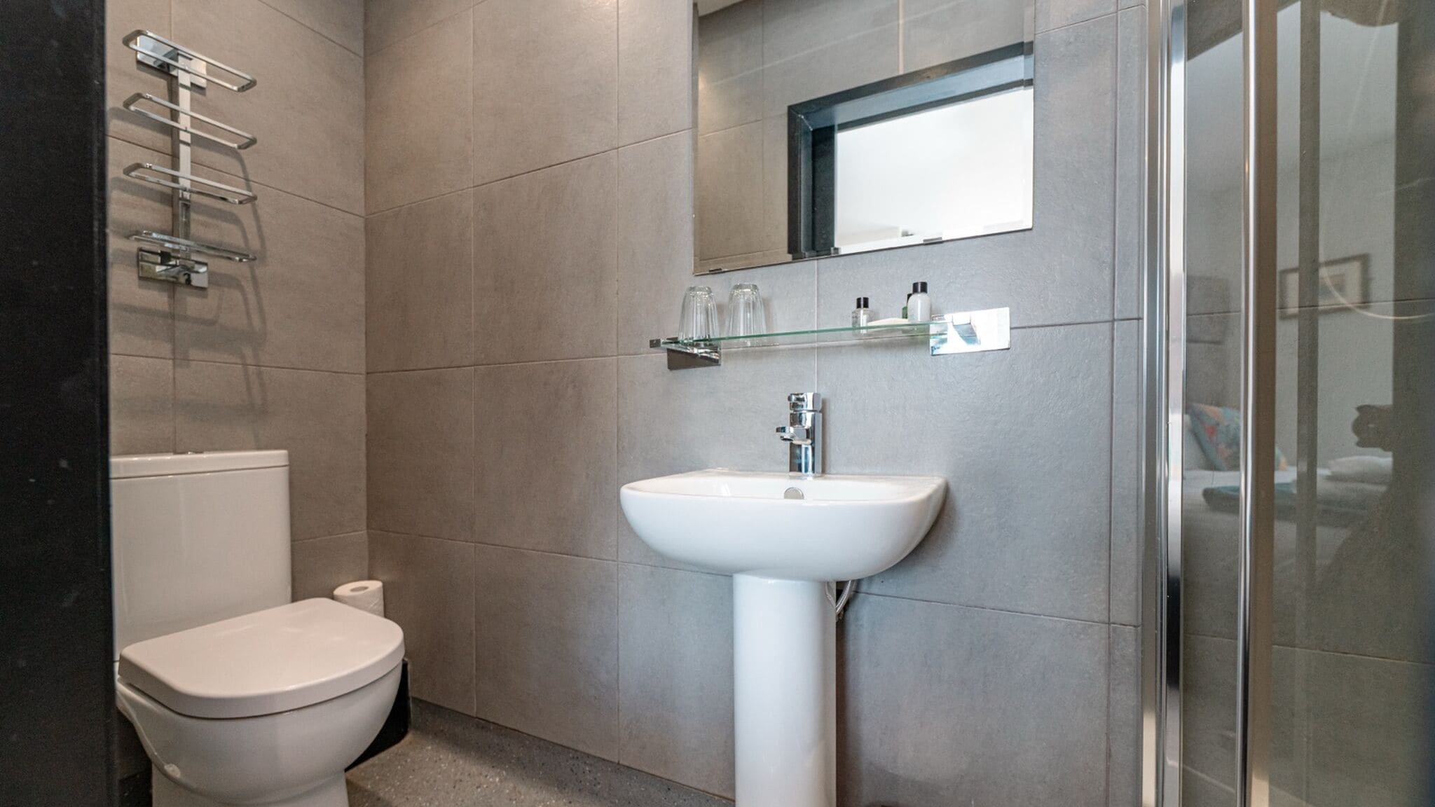 A modern bathroom with a toilet, a white sink, and a glass shower enclosure.
