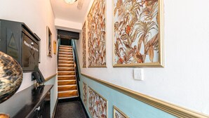 A hallway with a staircase, a wall-mounted keybox, and framed botanical artwork. - Sinclair's Bar, Lounge & Rooms (Southport)