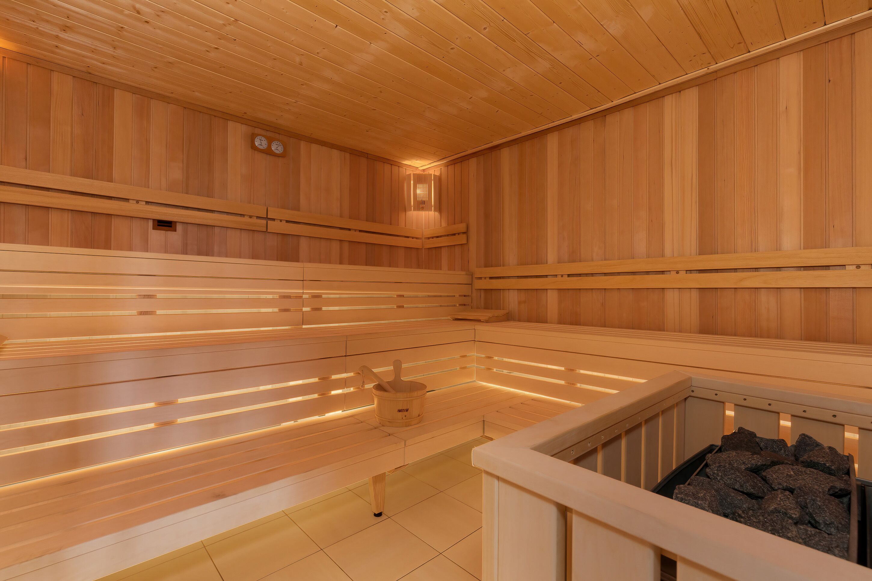 A sauna with wooden benches, a wooden floor, and a stone basin.