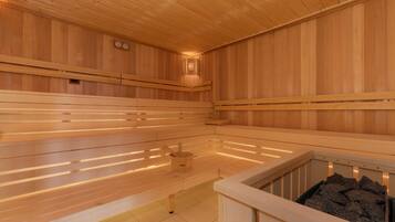 A sauna with wooden benches, a wooden floor, and a stone basin.