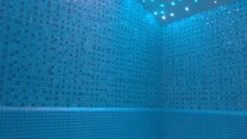 Relax by the pool in a serene, tile-lined space with a ceiling featuring a unique lighting pattern.