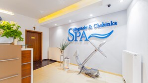 Ein Empfangsbereich mit einer Rezeption, einem an der Wand befestigten Schild mit der Aufschrift "Spa", einem Kreuz und einer dekorativen Anker.