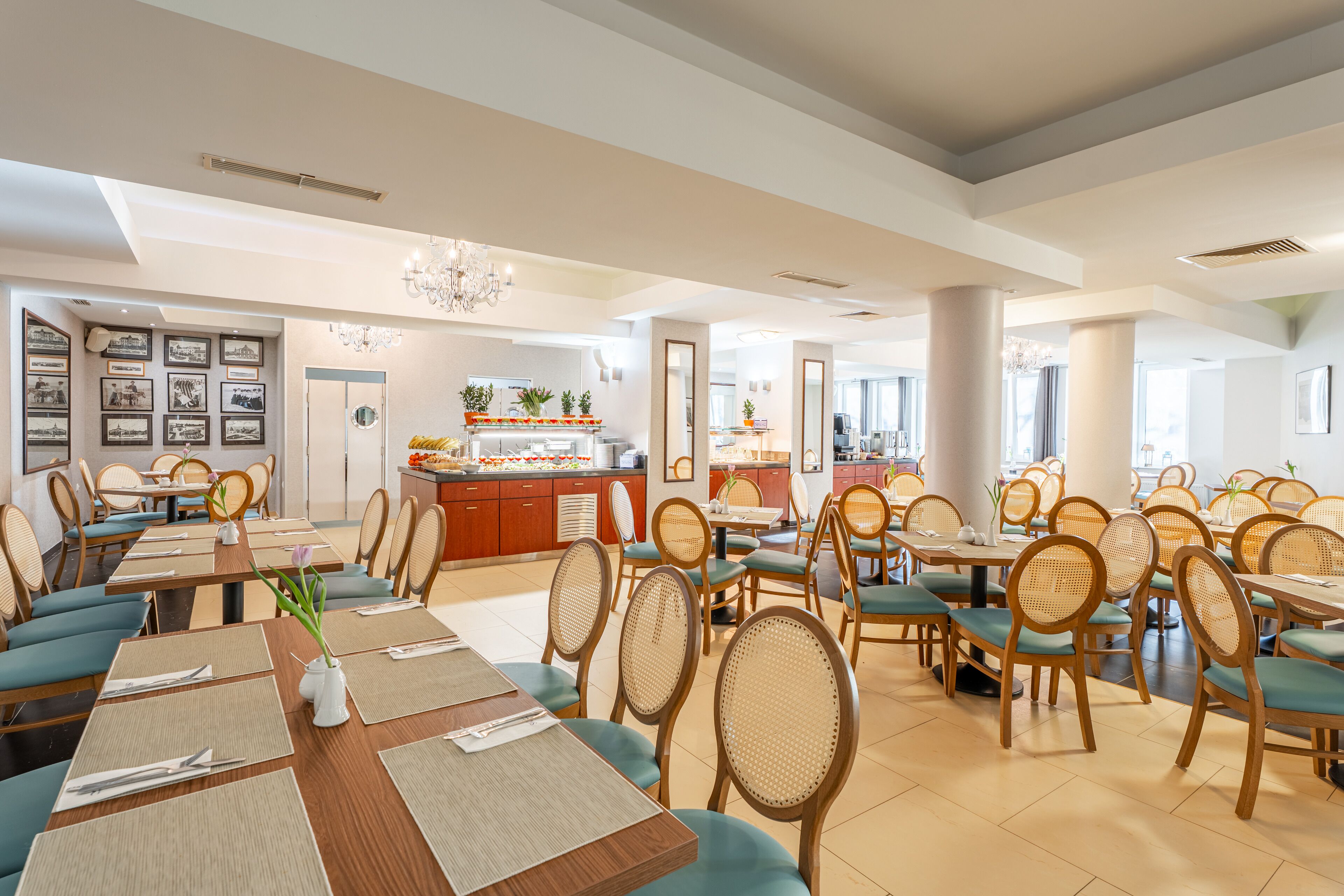 A spacious dining area with multiple tables and chairs, a central buffet, and framed pictures on the walls.