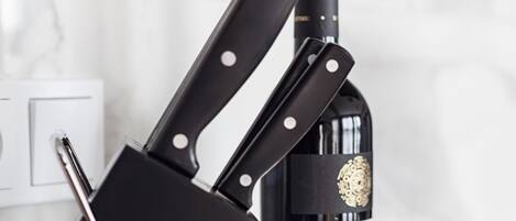 A knife block with two knives and a bottle of wine.