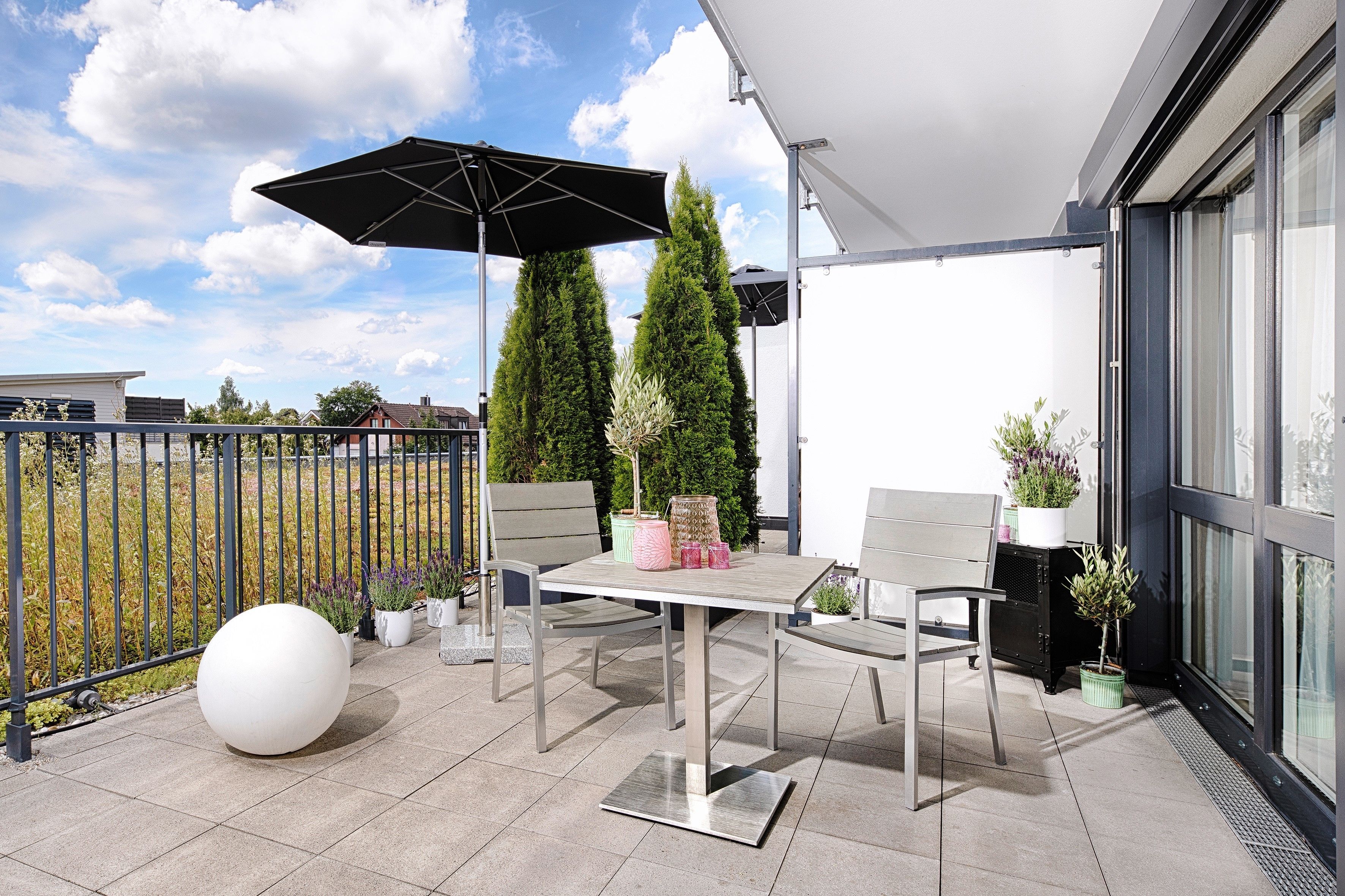An outdoor patio with a table and chairs, a large white spherical object, and potted plants.