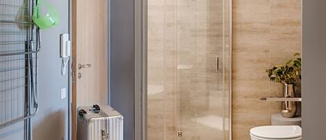 Un baño moderno con cabina de ducha de vidrio, inodoro y lavamanos.
