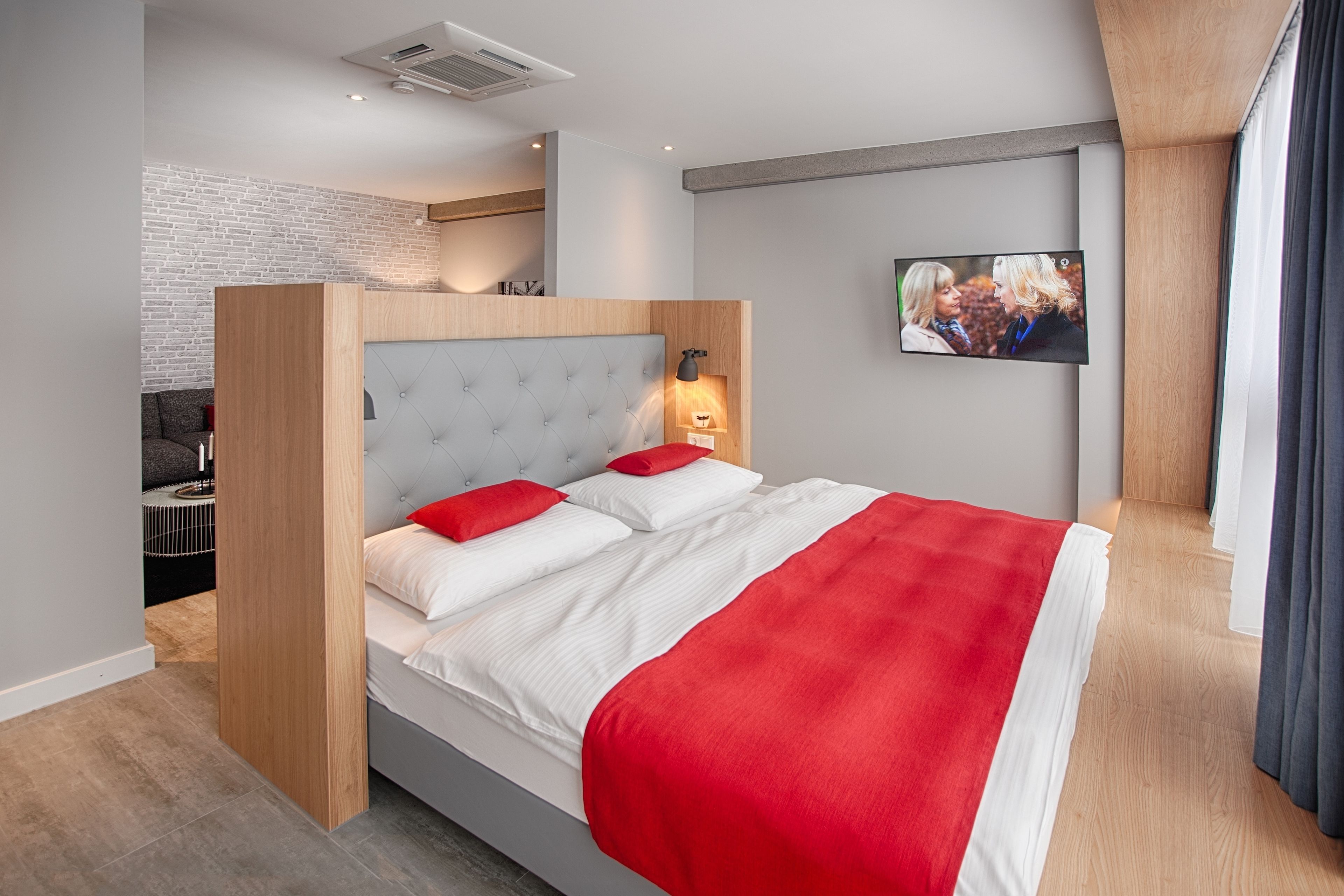 Habitación de hotel moderna con cama, televisor y vista a la ciudad.