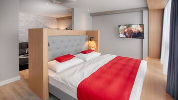 Habitación de hotel moderna con cama, televisor y vista a la ciudad.