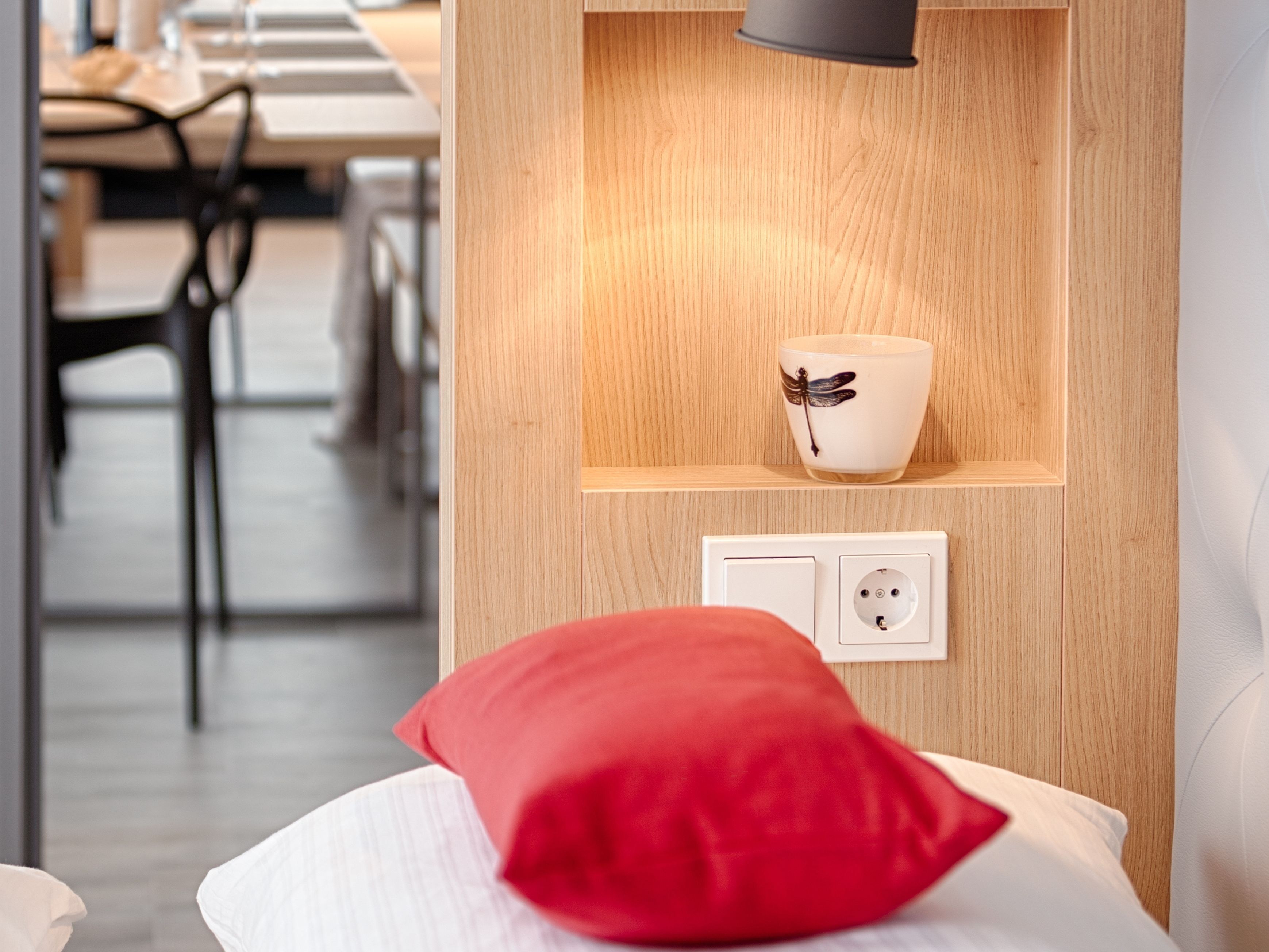 Ein modernes Zimmer mit einer Holzwand, einem roten Kissen, einem weißen Kissen und einer Wandleuchte.