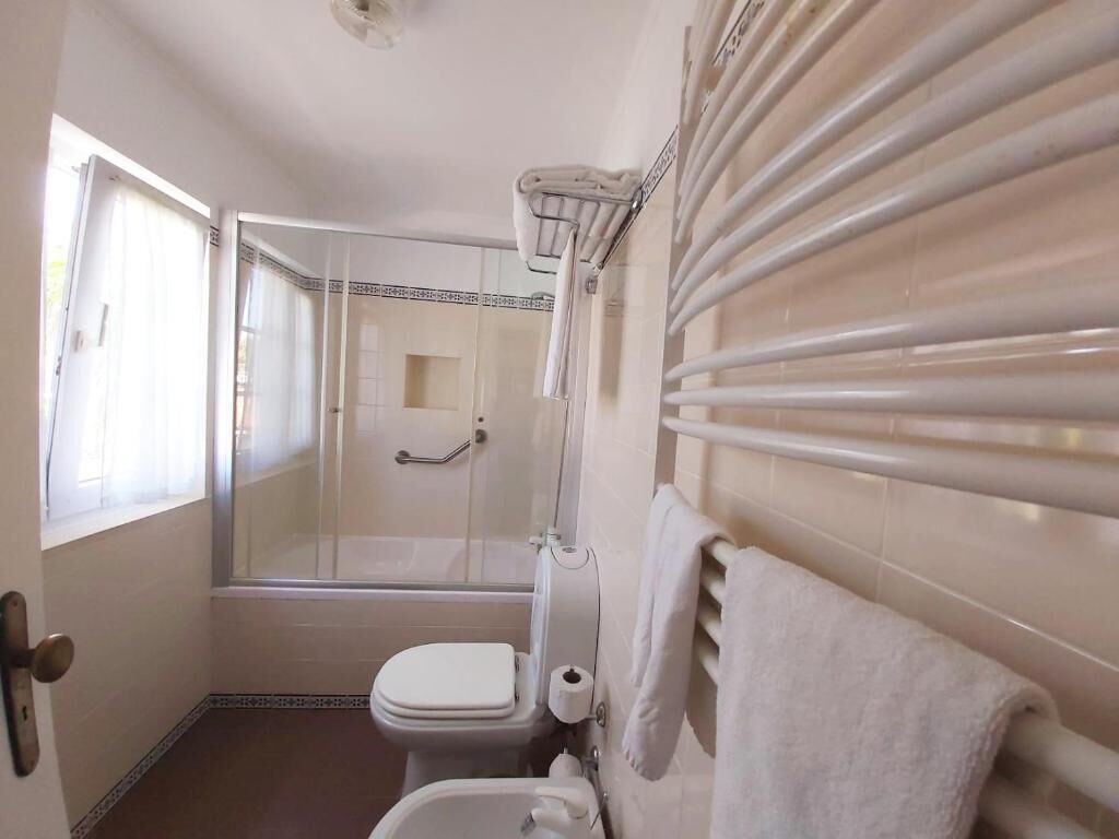 Ein Badezimmer mit Duschkabine aus Glas, Toilette und Handtuchhalter.