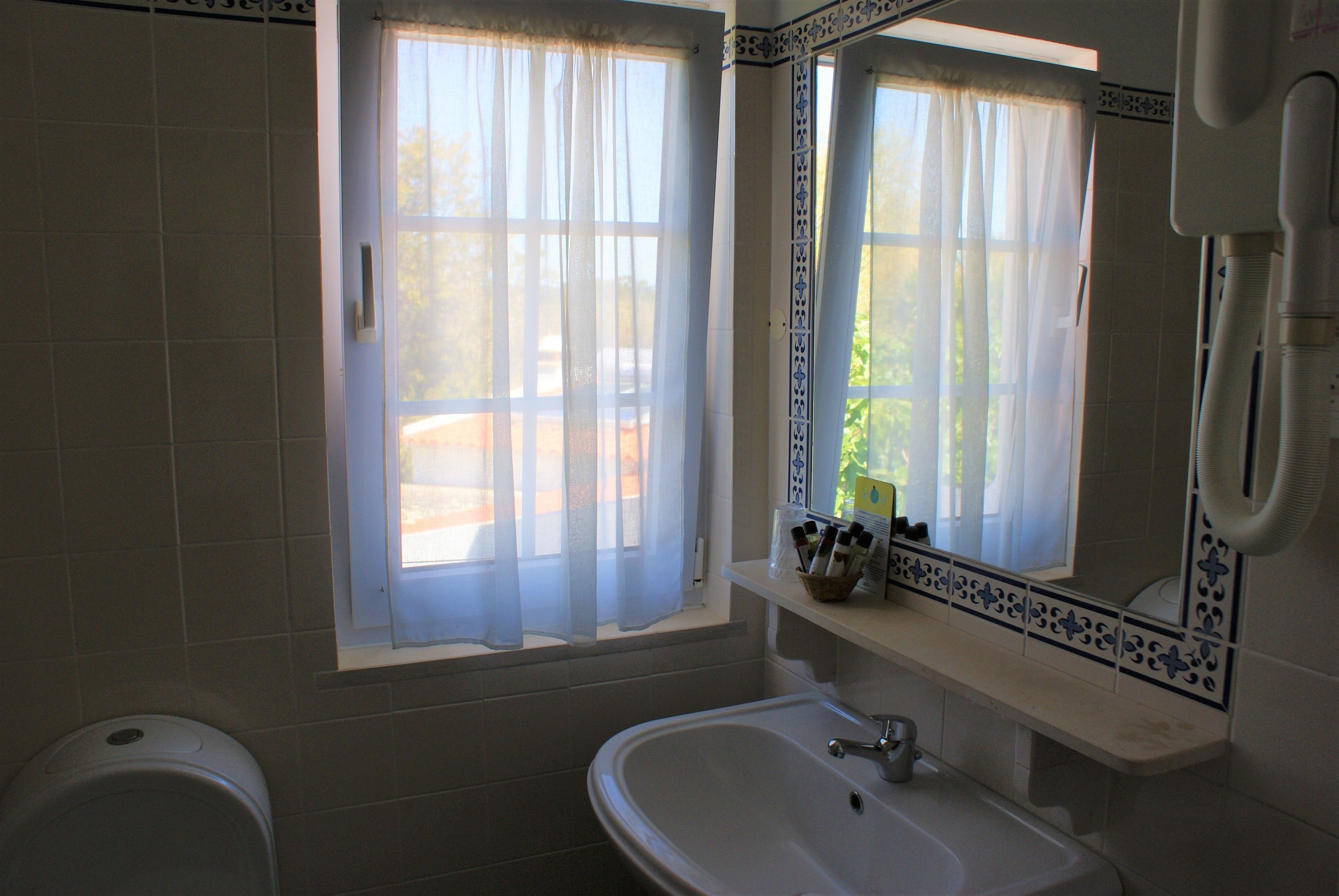 A bathroom with a window, a sink, and a toilet.