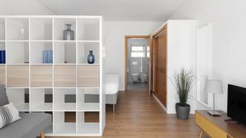 Una sala de estar moderna con un sofá, un televisor, una estantería y una planta en maceta.