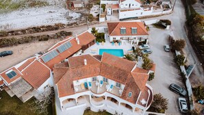 An aerial view of a residential area with multiple houses, a swimming pool, and a road.