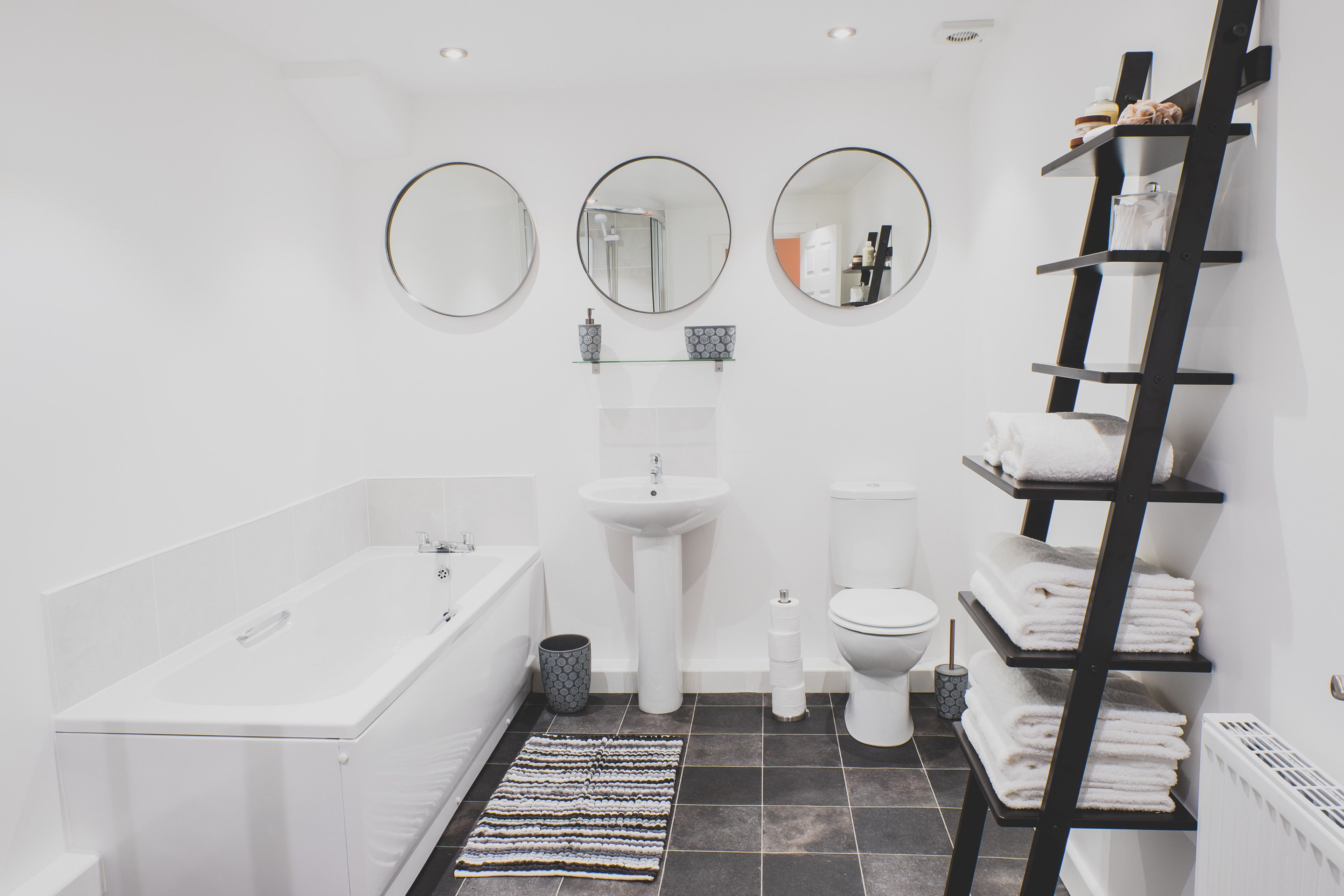 A modern bathroom with a bathtub, sink, toilet, and a towel rack.