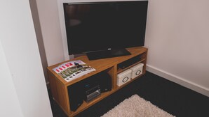 En möbel i trä som används för underhållning, med en platt-TV, ett stereosystem och tidskrifter.