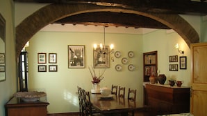 Un comedor con mesa de madera, sillas, una lámpara de araña y un sofá estampado con motivos florales.