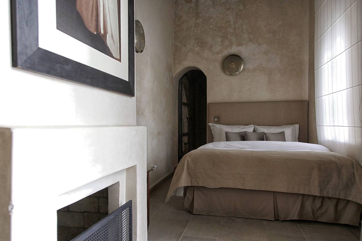 A bedroom with a large bed, a fireplace, and a view of the outside.