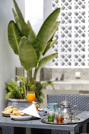 Una mesa dispuesta con tetera de plata, vasos y una bandeja con comida y bebidas.