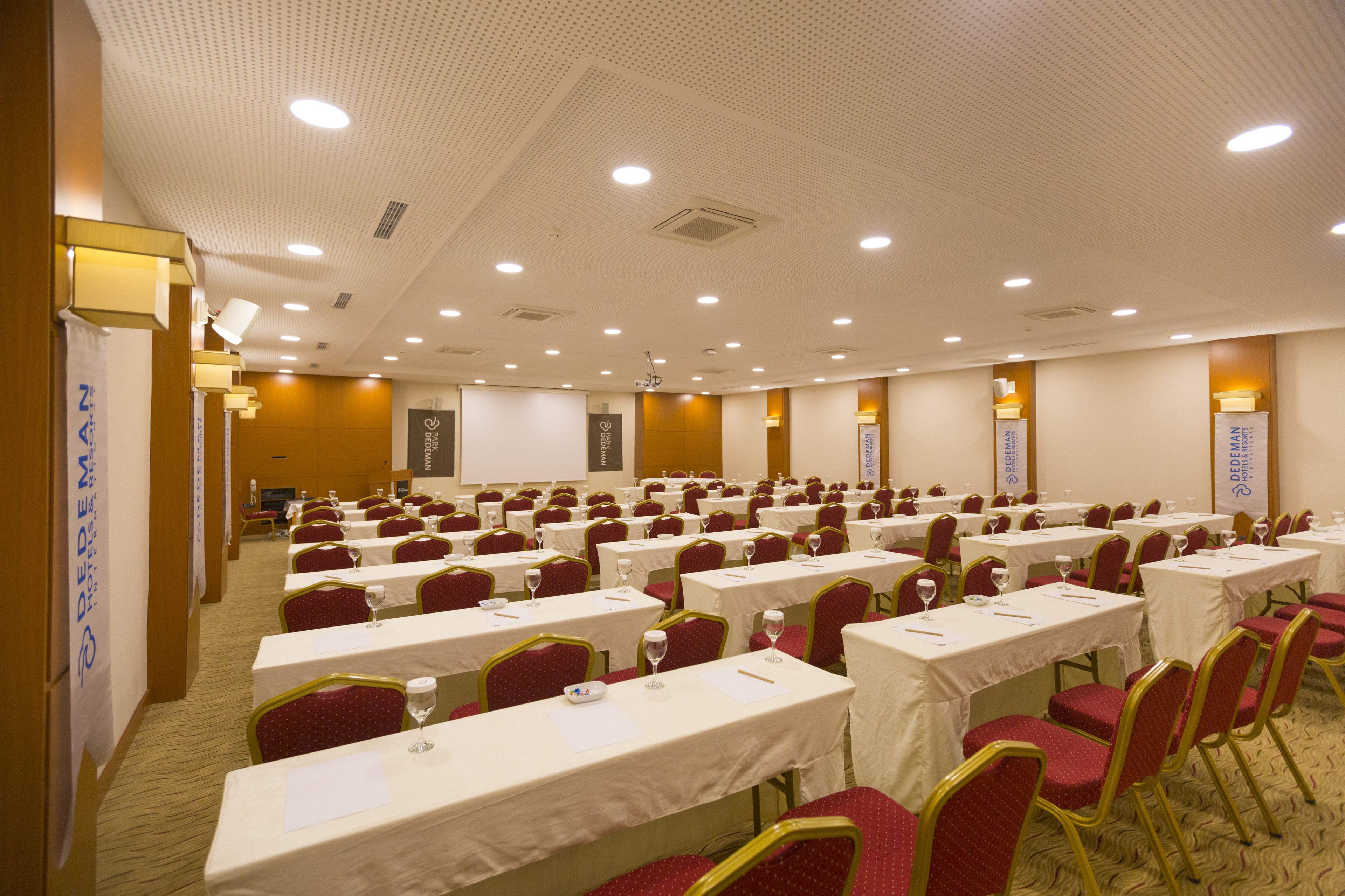 Une salle de conférence avec des rangées de tables et de chaises, équipée de plaques nominatives et de verres à eau.