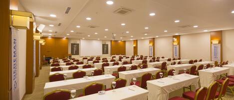 Une salle de conférence avec des rangées de tables et de chaises, équipée de plaques nominatives et de verres à eau.