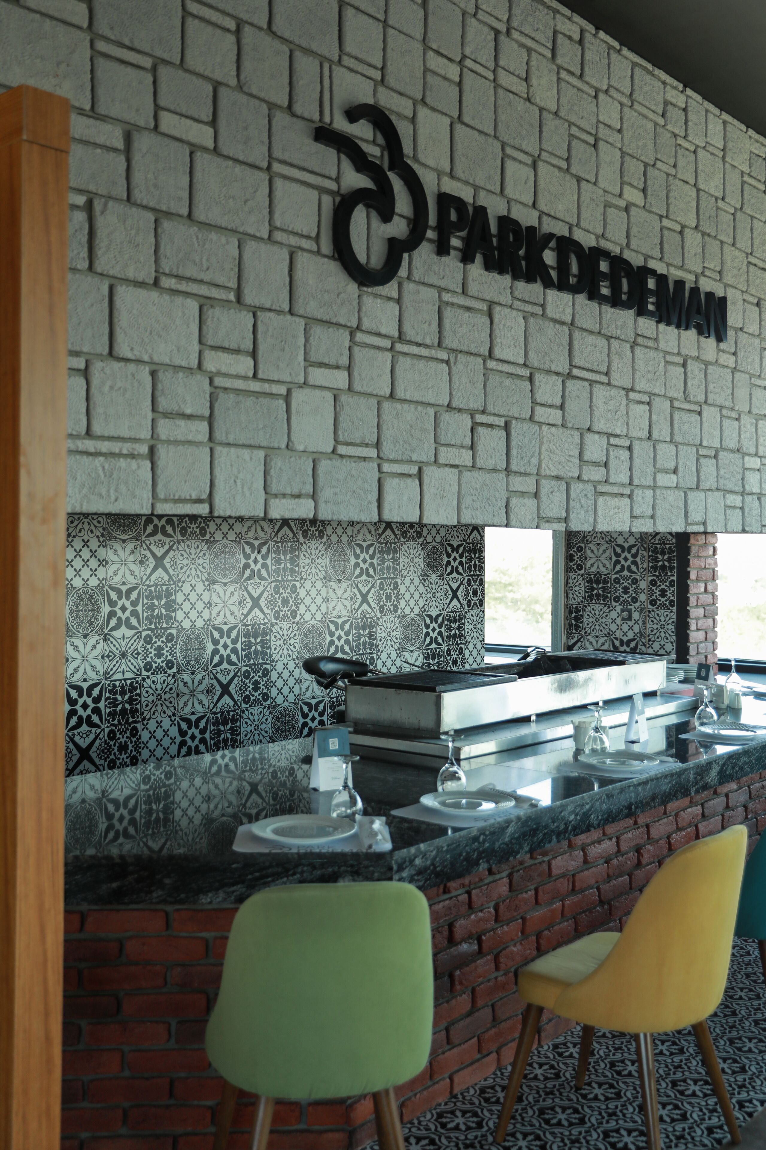A bar area with a brick wall, patterned tiles, and a sign reading "PARKDEDEMAN".