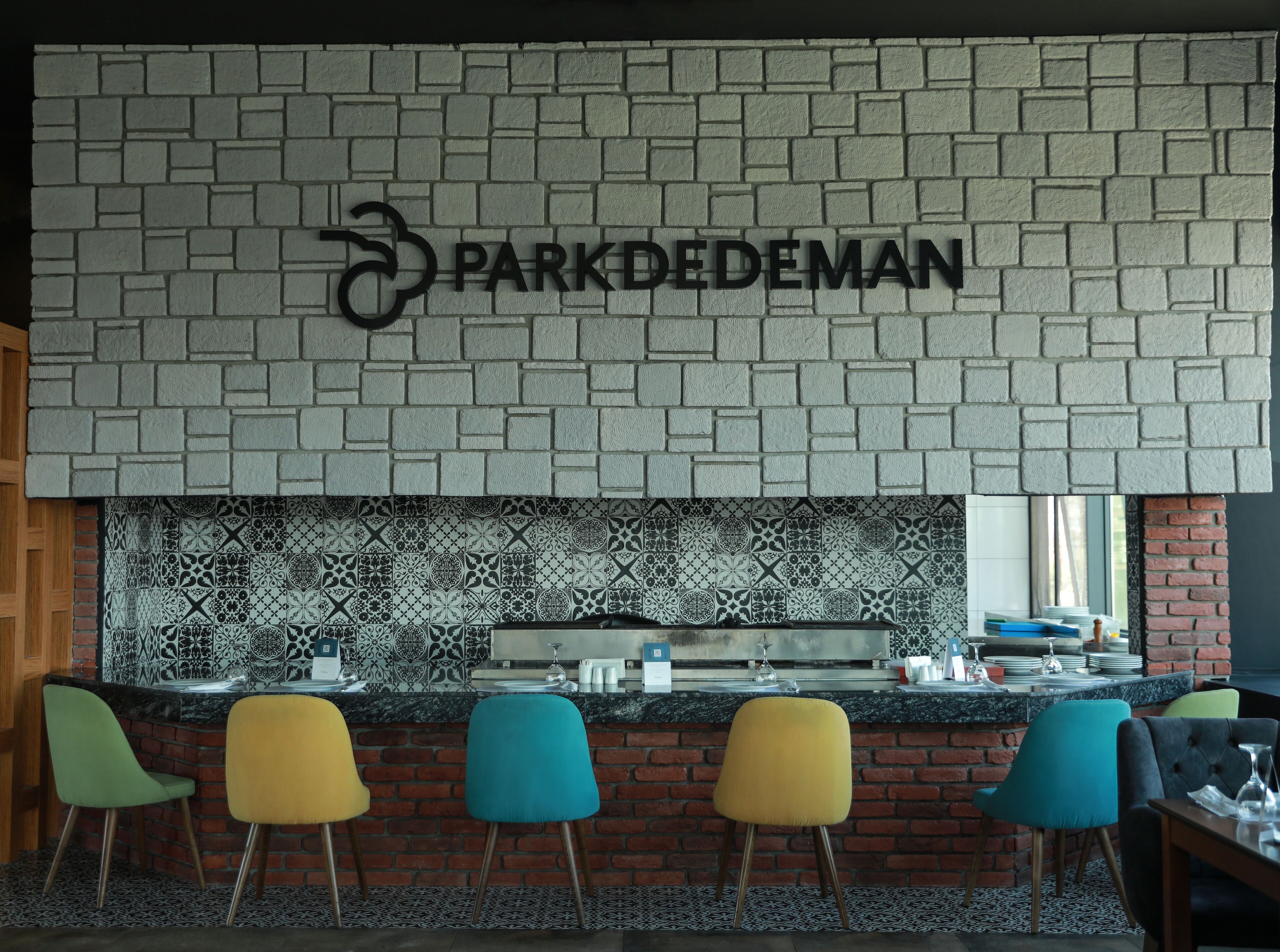 A bar area with a brick wall and a sign reading "PARKDEDEMAN".
