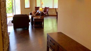 Ein großzügiger Wohnraum mit Deckenventilator, einer Holzkommode und einem Sofa.